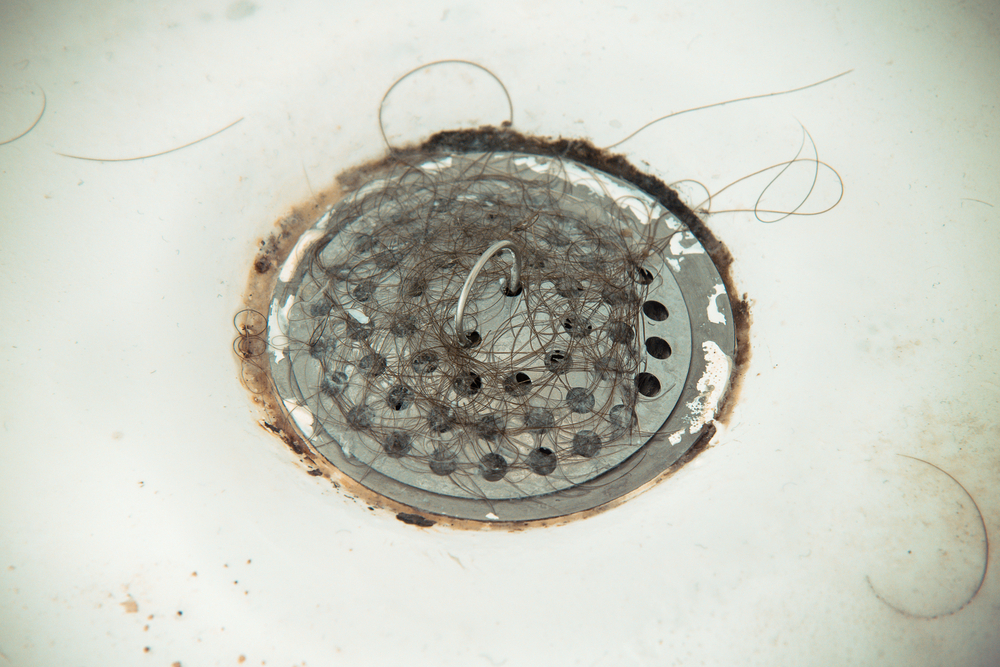 clogged shower drain covered in hair