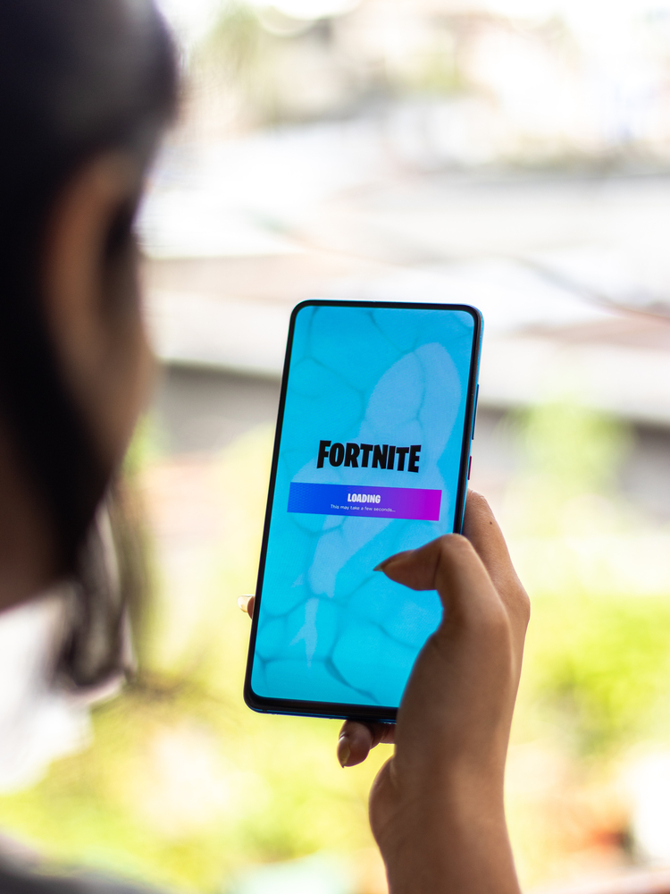 girl holding phone with fortnite app open